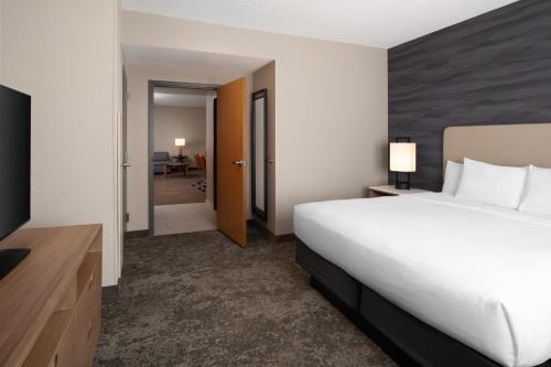 a hotel room with a bed and a desk and a hallway at Embassy Suites North Charleston Airport Hotel Convention in Charleston