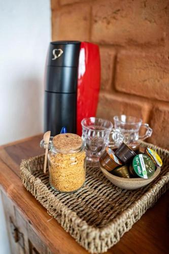 a table with a container of food and a coffee maker at Chafariz Por Um Triz Pousada de Charme in Tiradentes