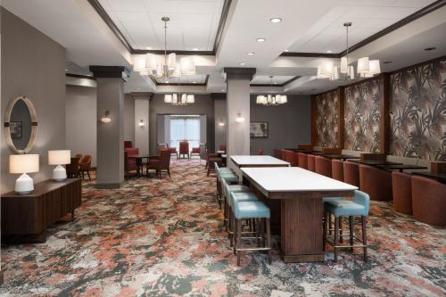 a lobby with tables and chairs in a room at Embassy Suites North Charleston Airport Hotel Convention in Charleston
