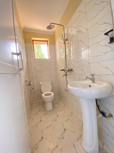 a white bathroom with a sink and a toilet at Kinyaiya's Sereniry Farmstay 