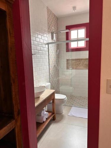 a bathroom with a toilet and a glass shower at Chafariz Por Um Triz Pousada de Charme in Tiradentes