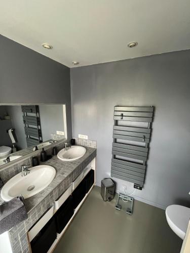 une salle de bain avec deux lavabos et un grand miroir dans l'établissement Maison avec piscine près de Bordeaux, à Bègles