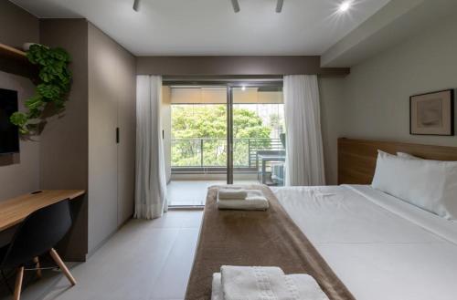 Un dormitorio con una cama y un escritorio y un balcón. en BHomy Caraibas, en São Paulo