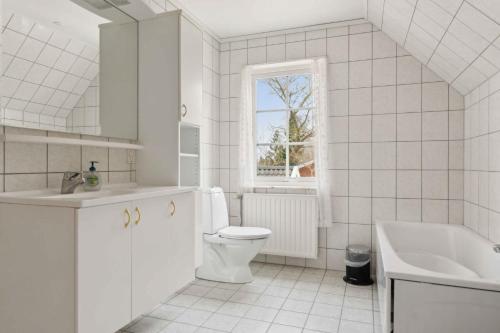 a white bathroom with a toilet and a sink at Spacious Villa In The Countryside Near The Beach in Fakse Ladeplads