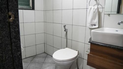 a white bathroom with a toilet and a sink at Hotel Prime Suites - Baner in Pune