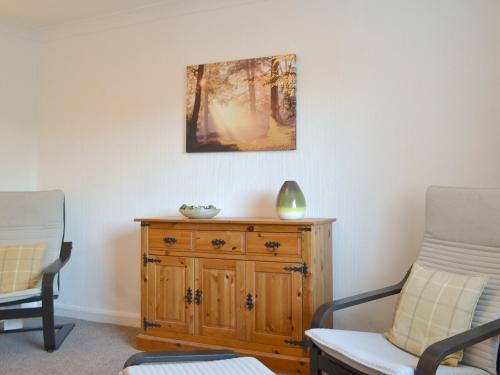 a living room with two chairs and a wooden dresser at The Farmhouse At Lane Foot in Tallentire