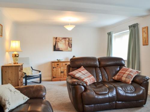 a living room with a leather couch and a chair at The Farmhouse At Lane Foot in Tallentire