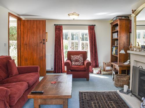 a living room with a couch and a chair at Myrtle Cottage in Puncknowle