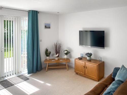 a living room with a couch and a flat screen tv at Blissful Ocean Breeze in Perranporth