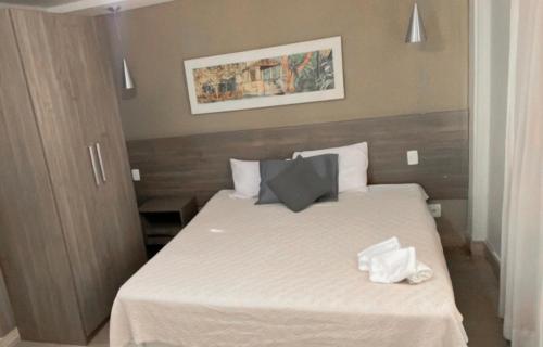 a bedroom with a bed with white sheets and towels at STOP Mar Suite Privada - NI in Nova Iguaçu