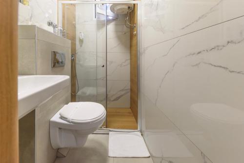 a white bathroom with a toilet and a shower at Garni Hotel Zenit in Novi Sad