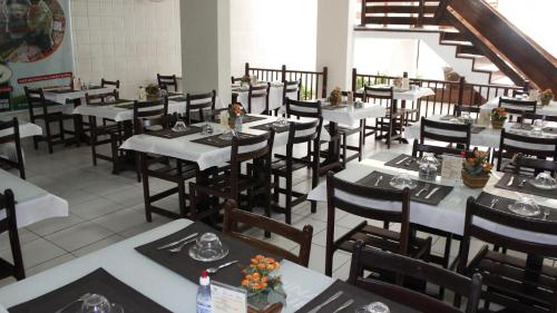 a dining room with white tables and chairs at Sirius Beach Hotel in Natal