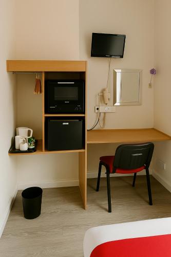 a room with a desk with a microwave and a chair at The Railway Sleeper Lodge in Colchester