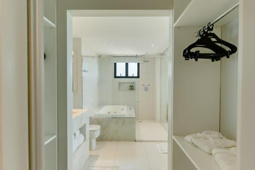 a white bathroom with a tub and a toilet at Meridiano Hotel in Maceió