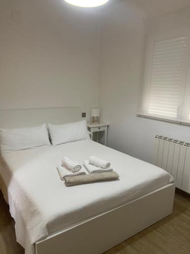 un letto bianco con due asciugamani sopra di Apartamentos Salma 20 a Toledo