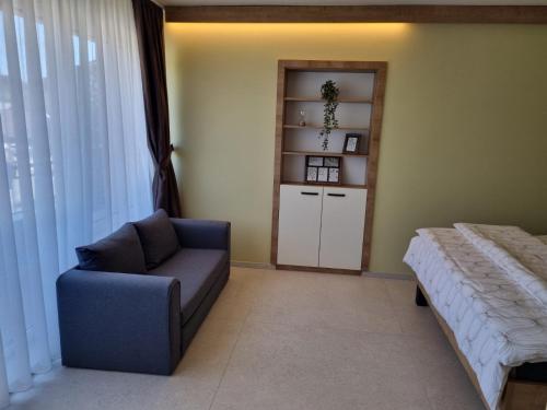a bedroom with a bed and a chair and a shelf at Mega Apartmaji in Rogaška Slatina