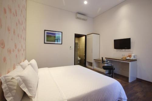 a hotel room with a white bed and a desk at Dago Teuku Angkasa 14 in Bandung