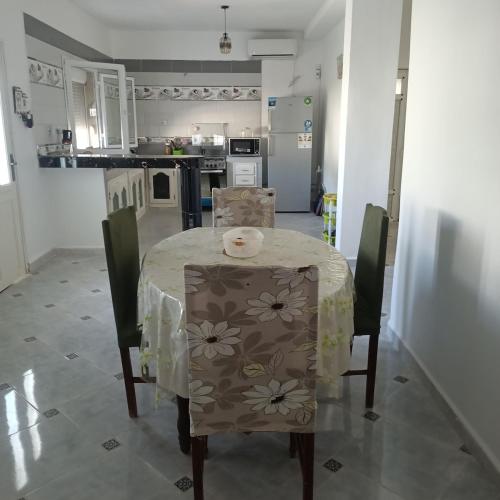 a kitchen with a table and chairs with a tablecloth on it at La maison des senteurs in El Kala