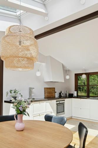 a kitchen with white cabinets and a wooden table at Architect Designed With Two Wings By Tisvilde Hegn in Tisvildeleje