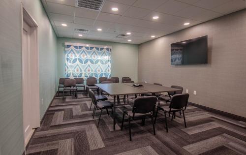 a conference room with a table and chairs and a screen at Tru by Hilton in McKinney