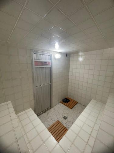 a white tiled bathroom with a shower in it at Pousada Vossa Excelência in Cajuru