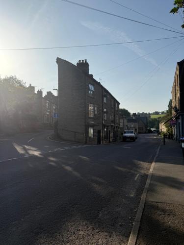 an empty street with a building and a car on the road at Woolpack Studio in Hayfield