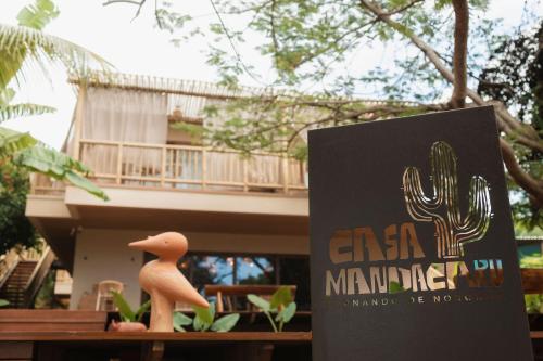 a sign in front of a building with a cactus statue at Pousada Casa Mandacaru Noronha in Fernando de Noronha
