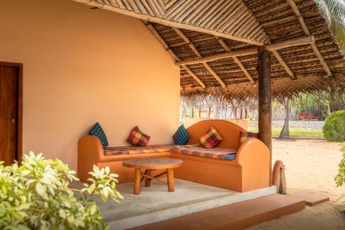 a couch under a pergola with a table at Roshanne Beach Resort in Kalpitiya