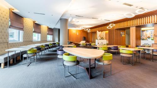 Un vestíbulo con mesas y sillas y una cafetería. en Golden Tulip Amnéville - Hôtel Spa & Casino, en Amnéville