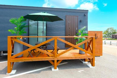 a wooden bench with an umbrella in front of a building at Trailer Ship Garden Aso - Vacation STAY 09150v in Aso