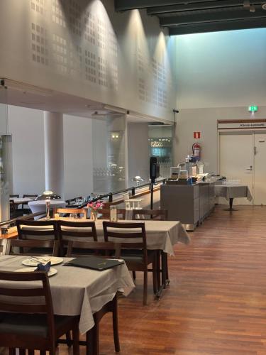 a restaurant with tables and chairs and a kitchen at Kraatterin Helmi Suite in Lappajärvi