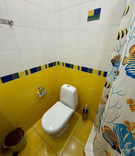 a bathroom with a toilet and a yellow and blue wall at Edem Hotel in Elar