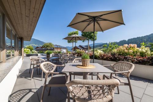 a patio with tables and chairs and an umbrella at Aparthotel Jägerheim in Flachau