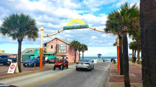 a street sign for a car dealership on a street with palm trees at Inn on the Avenue in New Smyrna Beach