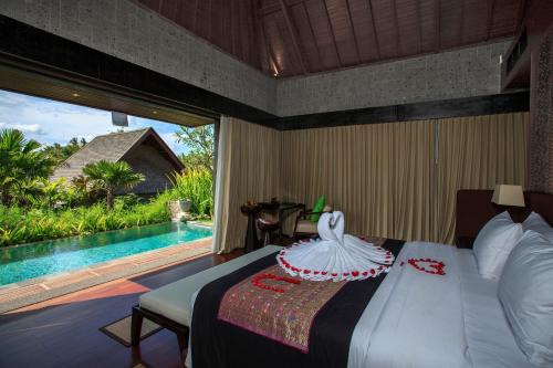 a bedroom with a bed and a swimming pool at Sanctoo Suites & Villas in Gianyar