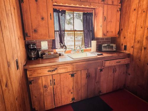a kitchen with wooden cabinets and a sink and a window at Room 4 - Downtown Joshua Tree Motel - Pet Friendly - Walk to Shops & Visitor Center, Minutes to Park Entrance in Joshua Tree