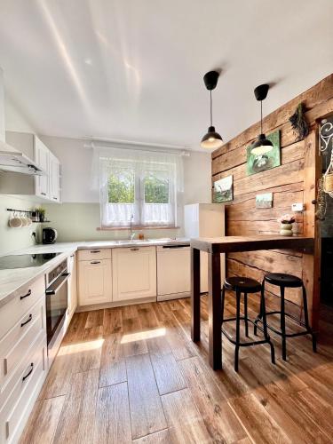 a kitchen with white cabinets and a wooden floor at Osinkowy Domek in Sobiatyn
