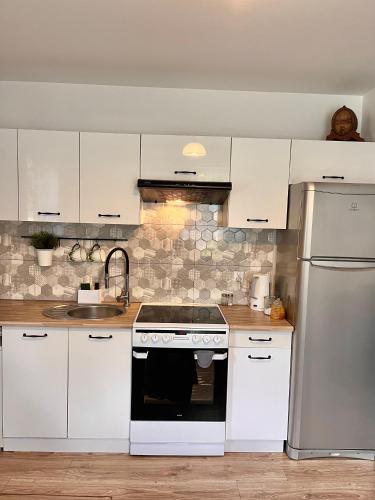 a kitchen with white cabinets and a stove top oven at Osinkowy Domek in Sobiatyn