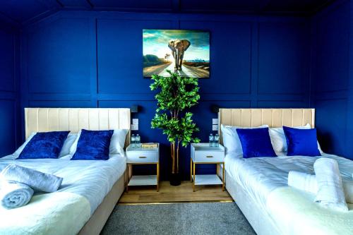two beds in a room with blue walls at Blue Haven House Sleeps 11 Garden & Parking in Orgreave