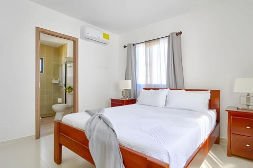 una camera da letto con un grande letto bianco e un bagno di Caribbean Punta Cana Paradise Villa a Punta Cana