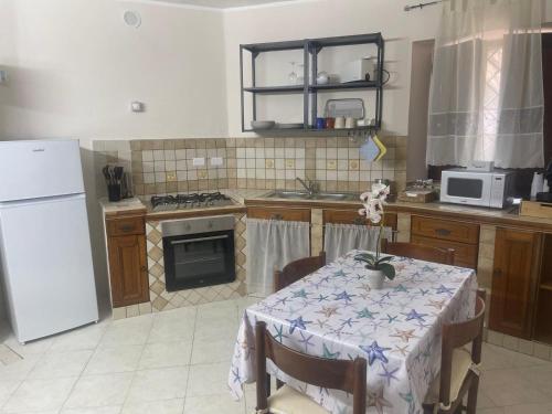 a kitchen with a table and a white refrigerator at Red House- Accogliente appartamento vicino al porto in Civitavecchia