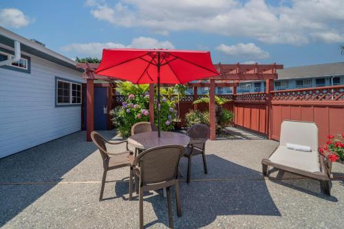 a table and chairs with a red umbrella on a patio at Best Western Country Inn in Fortuna