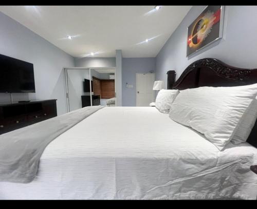a bedroom with a large white bed and a flat screen tv at Luxury Home Secured in Kingston