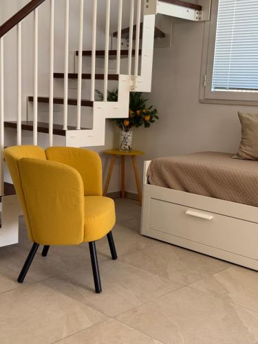 a bedroom with a yellow chair next to a bed at Casa MaLù in Aci Bonaccorsi