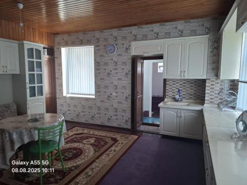 a kitchen with white cabinets and a table and a sink at Mountain view in Gabala in Bunud