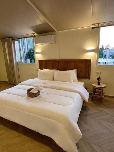 un grande letto bianco in una stanza con due finestre di Sukoun Studios a Baalbeck