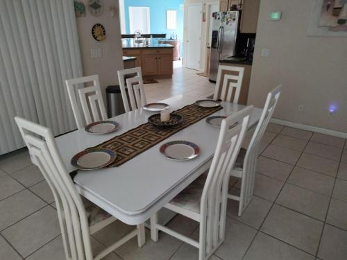 a white dining room table with white chairs and a kitchen at TheTotal Florida life style heated pool 5 bedrooms in Punta Gorda
