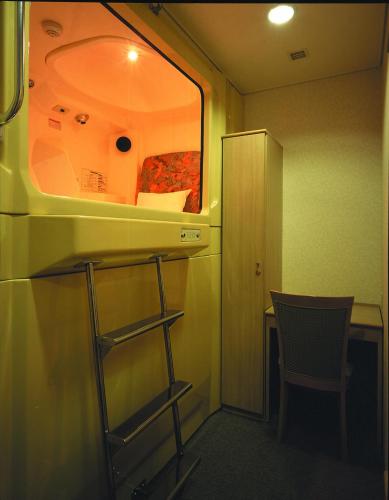 a room with a chair and a table and a window at Capsule&Spa Grand Sauna Shinsaibashi in Osaka