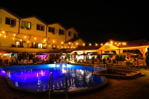a swimming pool at night with lights and a building at Elitte in Kavadarci