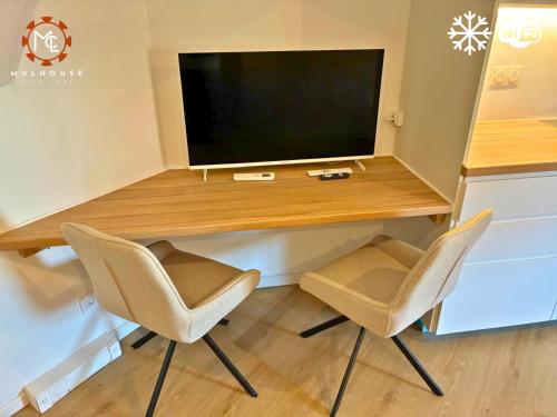 a desk with two chairs and a television on it at Mulhouse City Loft in Mulhouse